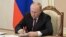 Vladimir Putin signs a document