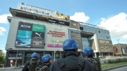 Спасатели возле здания пострадавшего от обстрела торгового центра в Запорожье. 25 мая 2022 года