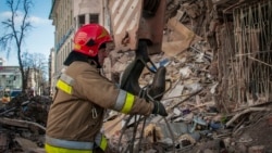Украинский пожарный работает возле разрушенного жилого дома в Харькове