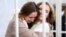 BELARUS -- Belsat TV journalists Katsyaryna Andreyeva and Daryya Chultsova, who were detained in November while reporting on anti-government protests, embrace each other in a defendant's cage during their trial in Minsk, February 18, 2021