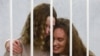 BELARUS -- Belsat journalists Katsyaryna Andreyeva (right) and Daryya Chultsova embrace each other in a cage before the start of a trial in Minsk, February 9, 2021