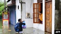 Мужчина помогает женщине, оказавшейся в частично затопленном доме на окраине Коломбо, Шри-Ланка, 29 ноября 2025 года