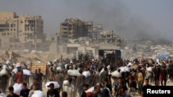 Жители Газы несут мешки с гуманитарной помощью в городе Бейт-Лахиа на севере сектора. 27 июля 2025 года